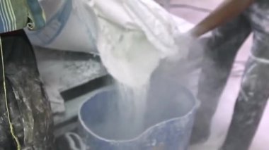 Fabrika işçisinin fabrikanın içindeki plastik bir kabın içindeki sabun tozunu çıkarması. Sabun üretimi.