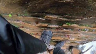 Bir adam ormanın ortasındaki su deresinin yanındaki ıslak kayalara tırmanıyor. Ormanda macera. ilham verici etkinlik