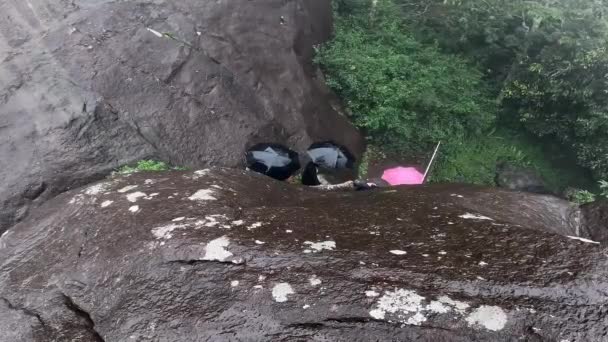 在雨天 游客们被夹在巨大的岩石之间 手里拿着雨伞 在丛林中探险 — 图库视频影像
