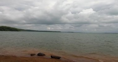 Güzel bir gölün panoramik manzarası ve yağmurlu bir günde orman ve dağların ortasındaki sığ göllerde dalgalar.