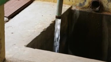 Fabrikanın tepesindeki paslı metal bir borudan akan suya yakın çekim. Metal bir borudan akan temiz su.