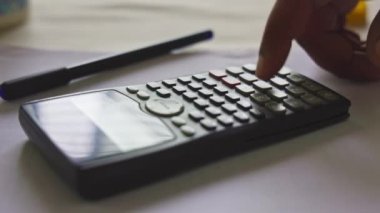 Kolaj ödevini yapmak için matematik fonksiyonu hesap makinesi ya da bilimsel hesap makinesi kullanan bir erkek öğrencinin yakınlaşması
