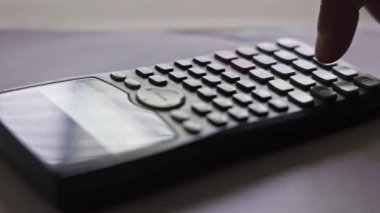 Kolaj ödevini yapmak için matematik fonksiyonu hesap makinesi ya da bilimsel hesap makinesi kullanan bir erkek öğrencinin yakınlaşması