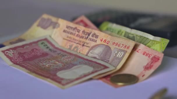 白いテーブルの上にインドのコインとお金が落ちる テーブルの上に通貨ノートに落ちるインドのルピーコインの閉鎖 ビジネス富の概念 — ストック動画