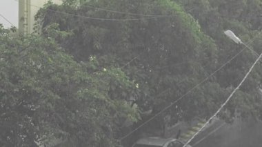 Balkonun manzarası şehir caddesinde şiddetli yağmur yağdığını gösteriyor. Şehirde yağmur yağıyor. Kötü hava. Şehirde sağanak var.