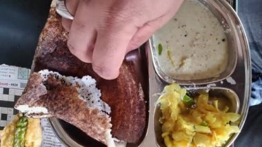 Sabah kahvaltısı olarak patates püresi ve hindistan cevizi turşusuyla masala dosa yiyen bir adamın yakın çekimi. Güney Hindistan yemekleri.