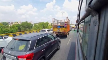 Bangalore, Hindistan-28 Nisan 2023: Otobüsün penceresinden yapılan bir görüntü, yaz aylarında seyahat sırasında otoyolda araçların geçişini veya aceleye getirilmesini gösteriyor