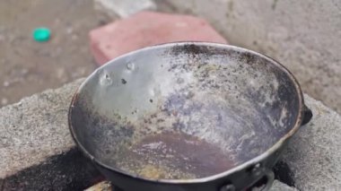 Hintli bir kadın, tuğla ocağın tavasında geleneksel yöntemle balık pişiriyor. Tuğla ocakta odun yakarak yemek pişiriliyor. Ahşap ateş