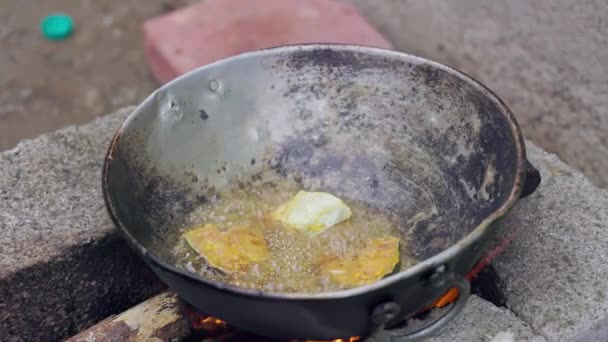 インド人女性が伝統的なスタイルでレンガのストーブの上で鍋に魚を揚げます 薪火料理 — ストック動画
