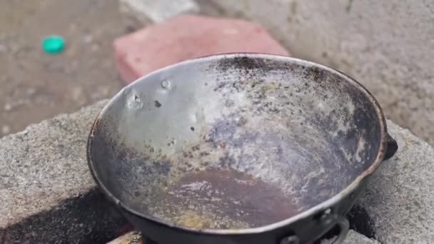 インド人女性が伝統的なスタイルでレンガのストーブの上で鍋に魚を揚げます 薪火料理 — ストック動画