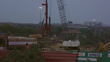 Bangalore, Hindistan-12 Mayıs 2023: Günbatımında vinçler, kamyonlar ve işçilerle birlikte inşaat alanının geniş bir görüntüsü. inşa alanı