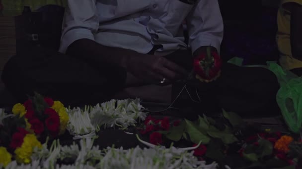 夕暮れ時に道端の花屋で結核のガーランドを作っている男の手の閉鎖 ビジネスコンセプト インド道端のお店 — ストック動画