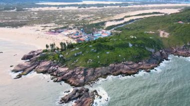 Joaquina Sahili 'nin yukarısından, plajın, kumulların ve kayalık kıyı şeridinin Florianopolis, Santa Catarina, Brezilya' daki Atlantik Ormanı ve turkuaz okyanusla çevrili yörüngesel görüntüsü..