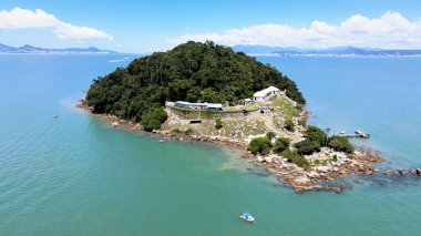 Florianpolis, Santa Catarina 'daki Santo Antnio de Ratones Kalesi' nin zümrüt yeşili bir okyanusta yüzen teknesiyle izole edilmiş bir ada üzerindeki havadan görüntüsü..
