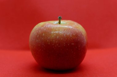 Kırmızı arka planda çiy damlaları olan taze kırmızı elma meyvesi