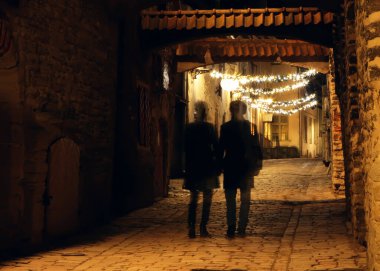Tallinn şehrindeki Old Town caddesinde birkaç Gölge. Sokakta Noel süsleri. Tarih ve klasik konsept