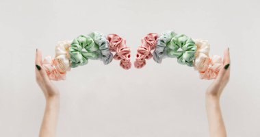 womas hands holding colorful scrunchies like crown on white banner. Hairdressing tools and accessories banner. Elastic Hair Bands levitation for girls