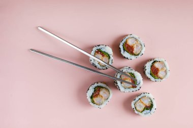 sushi rolls with shrimp on pink background. reusable sushi sticks. Food Photo with nobody. varieties of sushies, top view