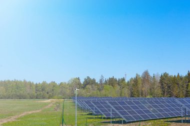 Gökyüzü arka planındaki güneş panelleri. Güneş enerjisi santrali. Mavi güneş panelleri. Alternatif elektrik kaynağı. Estonya 'da güneş çiftliği