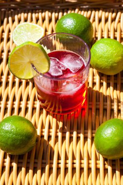 Kırmızı limonata ve güneş ışığında duran buzlu bardaklar. Çilekli içecek. Kokteyl Yaz mevsiminin limon suyunu samanla tazeliyor