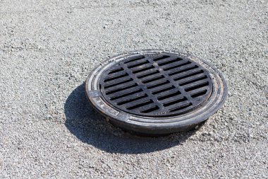 Kireçtaşı çakıl taşlarının üstüne demir kanalizasyon boşluğu dök. Yolda yağmur suyu için rögar Pavement