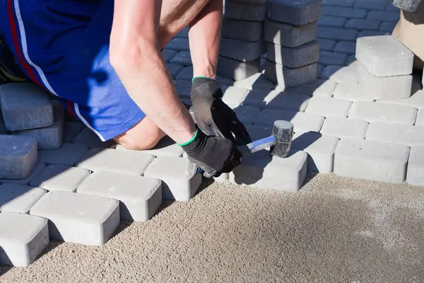 stock image man hands putting pedestrians street stones, pavement bricks. Bricklayer work on sidewalk and lays out paving slabs. working sight man in open air. Professional builder makes territory arrangement