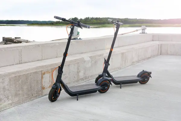 electric scooter on parking concrete pavement. gray background. sea side. Electric scooter on the city road. urban transportation readies to ride - bikes with accumulators in estonian city