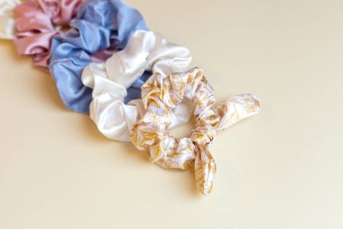 Bej arka planda bir sürü renkli ipek parşömen var. Düz yatıyordu. Kuaför aletleri ve aksesuarlar. Lastik saç bantları, Bobble Spor Saç bandı Yukarıdan