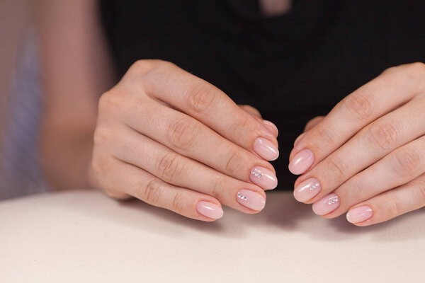 woman hands with manicure- nail polish on client nails during a manicure session at a beauty salon