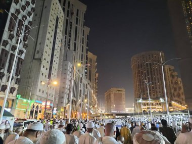 Mescid-i Haram 'ın dış yolundaki hacıların, yüksek binaların ve ışıkların güzel manzarası..