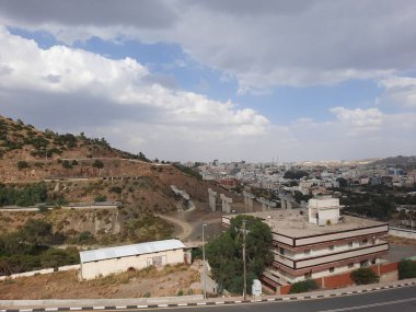 Suudi Arabistan 'daki Al Bahah şehrinin güzel gündüz gökyüzü manzarası. Arka planda şehir binaları, tepeler ve bulutlar görülüyor..