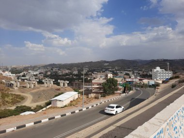 Suudi Arabistan 'daki Al Bahah şehrinin güzel gündüz gökyüzü manzarası. Arka planda şehir binaları, tepeler ve bulutlar görülüyor..