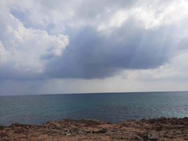  Stunning panoramic view of the Farasan Islands in Jazan, Saudi Arabia. The transparent waters, rocky formations, and looming dark clouds create a picturesque landscape. clipart