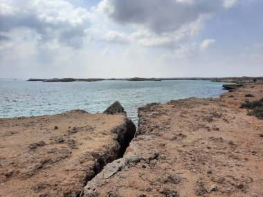 Suudi Arabistan, Jazan 'daki Farasan Adaları' nın çarpıcı panoramik manzarası. Şeffaf sular, kayalık oluşumlar ve yaklaşan kara bulutlar muhteşem bir manzara yaratır..