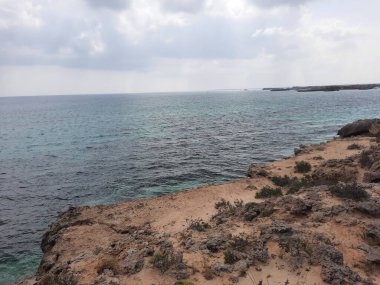 Suudi Arabistan, Jazan 'daki Farasan Adaları' nın çarpıcı panoramik manzarası. Şeffaf sular, kayalık oluşumlar ve yaklaşan kara bulutlar muhteşem bir manzara yaratır..