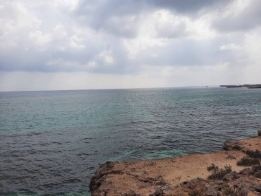 Suudi Arabistan, Jazan 'daki Farasan Adaları' nın çarpıcı panoramik manzarası. Şeffaf sular, kayalık oluşumlar ve yaklaşan kara bulutlar muhteşem bir manzara yaratır..