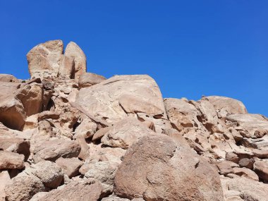 Al Bada, Tabuk 'taki Split Rock of Horeb çevresindeki dağların çarpıcı gündüz görüntüsü. Split Horeb Kayası, batıda Tabuk bölgesinde Al Bada yakınlarında bulunan Jabal Al Lawz üssünde yer almaktadır..