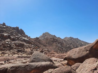 Al Bada, Tabuk 'taki Split Rock of Horeb çevresindeki dağların çarpıcı gündüz görüntüsü. Split Horeb Kayası, batıda Tabuk bölgesinde Al Bada yakınlarında bulunan Jabal Al Lawz üssünde yer almaktadır..