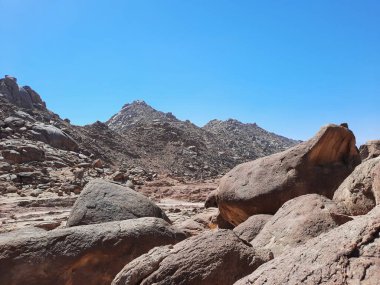 Al Bada, Tabuk 'taki Split Rock of Horeb çevresindeki dağların çarpıcı gündüz görüntüsü. Split Horeb Kayası, batıda Tabuk bölgesinde Al Bada yakınlarında bulunan Jabal Al Lawz üssünde yer almaktadır..
