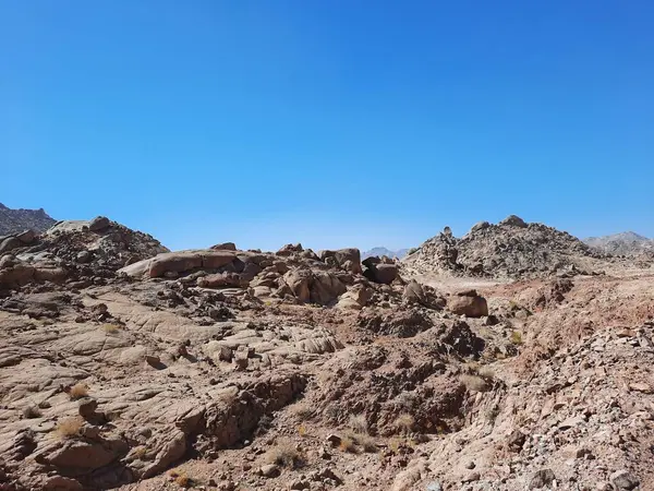 Al Bada, Tabuk 'taki Split Rock of Horeb çevresindeki dağların çarpıcı gündüz görüntüsü. Split Horeb Kayası, batıda Tabuk bölgesinde Al Bada yakınlarında bulunan Jabal Al Lawz üssünde yer almaktadır..