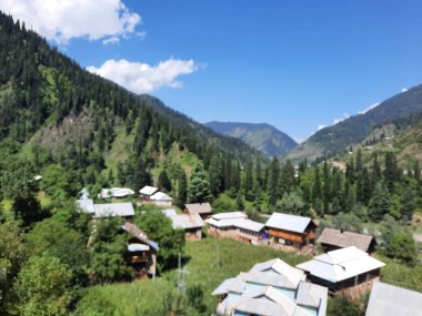  Kaşmir 'in Neelum Vadisi' ndeki Halmat köyünün göz kamaştırıcı bir perspektifi. Canlı yeşil ağaçlar, görkemli dağlar ve bol bitki örtüsü manzaralı bir manzara yaratır..