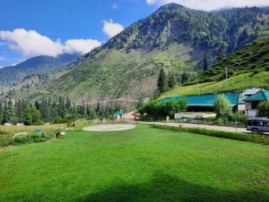  Kaşmir 'in Neelum Vadisi' ndeki Halmat köyünün göz kamaştırıcı bir perspektifi. Canlı yeşil ağaçlar, görkemli dağlar ve bol bitki örtüsü manzaralı bir manzara yaratır..