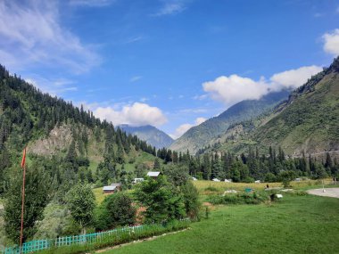 Kaşmir 'in Neelum Vadisi' ndeki Halmat köyünün göz kamaştırıcı bir perspektifi. Canlı yeşil ağaçlar, görkemli dağlar ve bol bitki örtüsü manzaralı bir manzara yaratır..