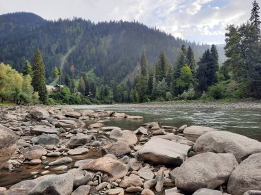  Kaşmir 'in Neelum Vadisi' ndeki Halmat köyünün göz kamaştırıcı bir perspektifi. Canlı yeşil ağaçlar, görkemli dağlar ve bol bitki örtüsü manzaralı bir manzara yaratır..