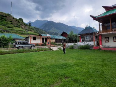  Kaşmir 'in Neelum Vadisi' ndeki Halmat köyünün göz kamaştırıcı bir perspektifi. Canlı yeşil ağaçlar, görkemli dağlar ve bol bitki örtüsü manzaralı bir manzara yaratır..