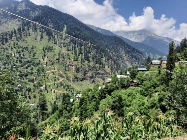 Yeşil manzaralardan, yüksek tepelerden ve gelişen ağaçlardan oluşan büyüleyici bir gündüz manzarası Kashmir 'in Neelum Vadisi' ndeki Jagran Vadisi 'nde tünemiş olan Shal köyünün etrafını sarmış durumda..