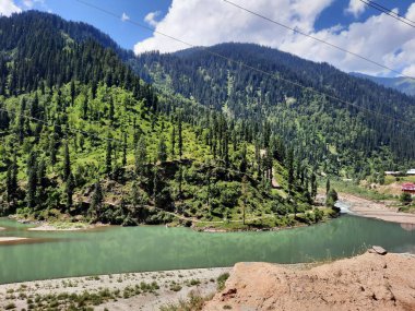 Kaşmir 'deki Neelum Vadisi' nin göz kamaştırıcı gündüz manzarası. Kaşmir 'deki Neelum Vadisi nefes kesici bir yerdir. Bereketli yeşil manzarası, uzun ağaçları ve canlı yeşilliği cennete benzer bir manzara yaratır..