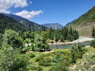 Kaşmir 'deki Neelum Vadisi' nin göz kamaştırıcı gündüz manzarası. Kaşmir 'deki Neelum Vadisi nefes kesici bir yerdir. Bereketli yeşil manzarası, uzun ağaçları ve canlı yeşilliği cennete benzer bir manzara yaratır..