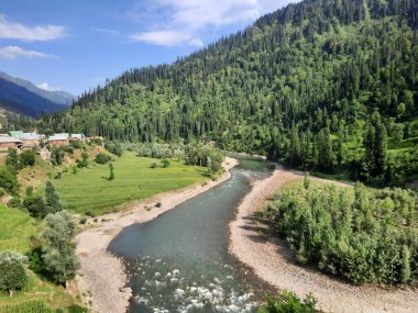 Kaşmir 'deki Neelum Vadisi' nin göz kamaştırıcı gündüz manzarası. Kaşmir 'deki Neelum Vadisi nefes kesici bir yerdir. Bereketli yeşil manzarası, uzun ağaçları ve canlı yeşilliği cennete benzer bir manzara yaratır..