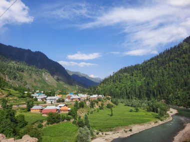 Kaşmir 'deki Neelum Vadisi' nin göz kamaştırıcı gündüz manzarası. Kaşmir 'deki Neelum Vadisi nefes kesici bir yerdir. Bereketli yeşil manzarası, uzun ağaçları ve canlı yeşilliği cennete benzer bir manzara yaratır..